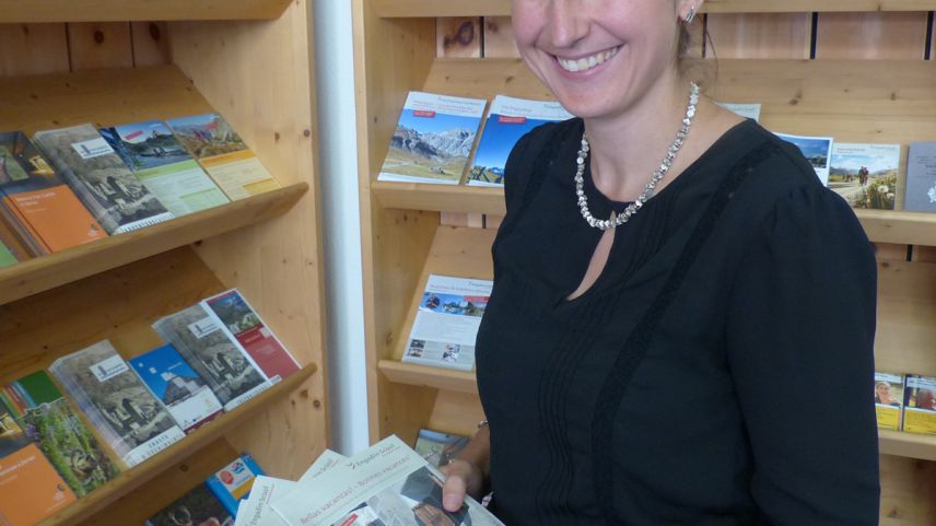 Martina Stadler, la directura da la destinaziun turistica TESSVM, cun broschüras per infuormar ils giasts da la region in differentas linguas. fotografia: Flurin Andry