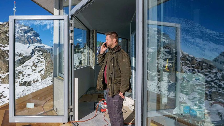 Pascal Mittner am Eingang zur Orma-Whisky-Destillerie auf der Corvatsch-Bergstation. Er erfährt gerade am Telefon von seinem Geschäftspartner Rinaldo Willy, dass an diesem Dienstag keine Heliflüge stattfinden können. Foto: Jon Duschletta