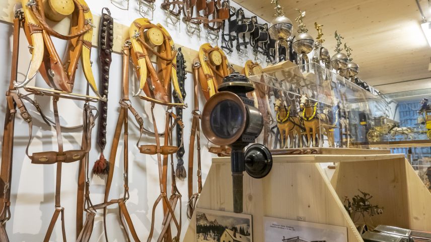 Bündner Geschirre an der Wand, diverse Kutschenlampen, Halfter und auch ein Postkutschen-Modell sind Teil der Sammlung.