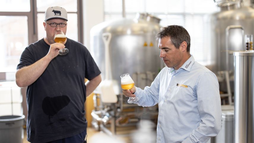 Il bierer Christian Schneider (a schnestra) e’l mainagestiun Reto Rauch prouvan co cha la biera gusta (fotografia: Dominik Täuber).