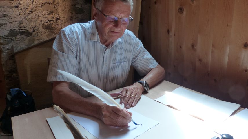 Theodor Gut, chi’d es commember dal cussagl da fundaziun dal museum Stamparia Strada, scriva culla penna d’ocha (fotografia: Flurin Andry).