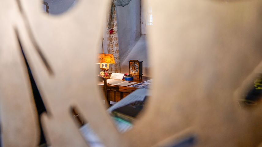 Blick durch eine Dekorationsschablone auf Exponate der Ausstellung «Die Uhr» im Kulturarchiv Oberengadin in Samedan. Foto: Jon Duschletta