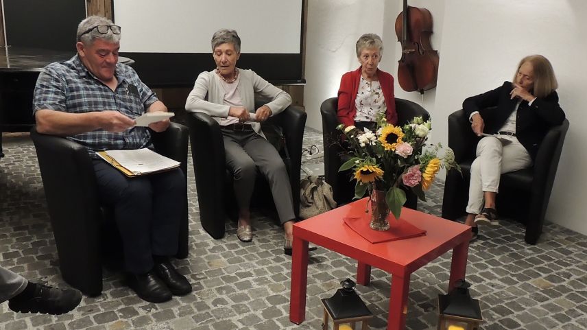 Armon Parolini cun Valerie Dolfi, Bernadette Bezzola e Mia Mathis han orientà davart l’istorgia da la biblioteca populara a Scuol (fotografia: Benedict Stecher).