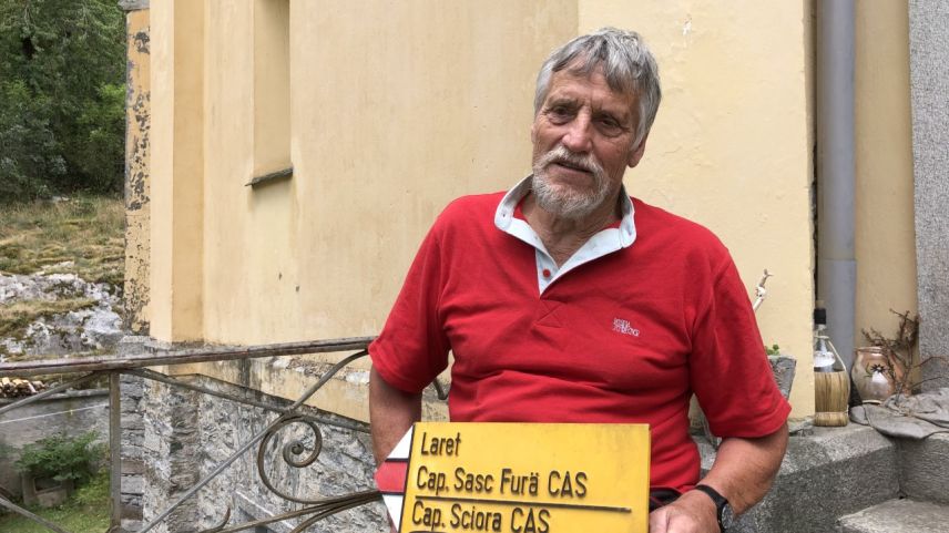 Arturo Giovanoli vor dem Eingang seines Wohnhauses mit einem gelben Wegweiser. Das Schild wurde ihm geschenkt.             Foto: Marie-Claire Jur