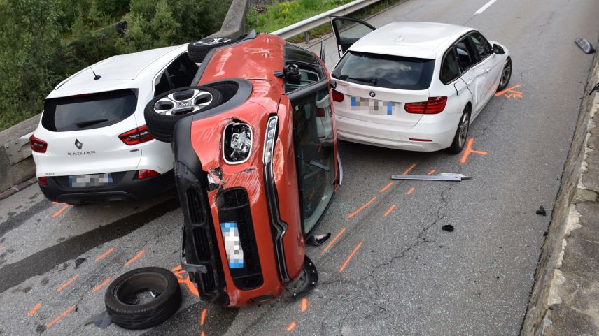 Zwischen zwei weissen Autos liegt das rote Auto der Italienerin auf der Seite (Foto: Kantonspolizei Graubünden).