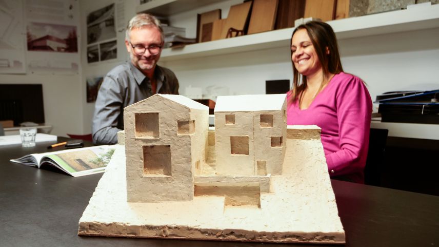 Die beiden Geschäftsführer mit einem Plastilinmodell der Steinhäuser Cad’Maté in Maloja, welche 2026 gebaut werden sollen. Foto: Jon Duschletta