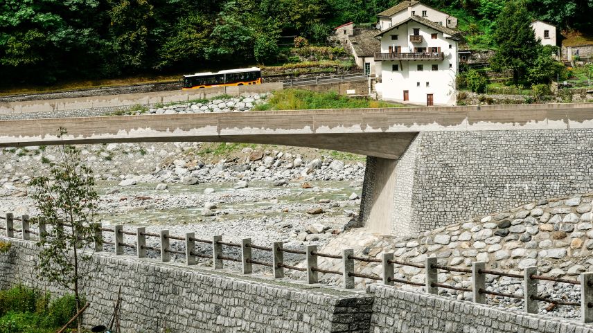 Blick von Bondo in Richtung Sottoponte und der neuen, um über fünf Meter erhöhten Kantonsstrassenbrücke Bondasca (Bildmitte) über dem Zusammenfluss von Maira und Bondasca sowie dem neuen Dammweg entlang des Rückhaltebeckens im Vordergrund. 