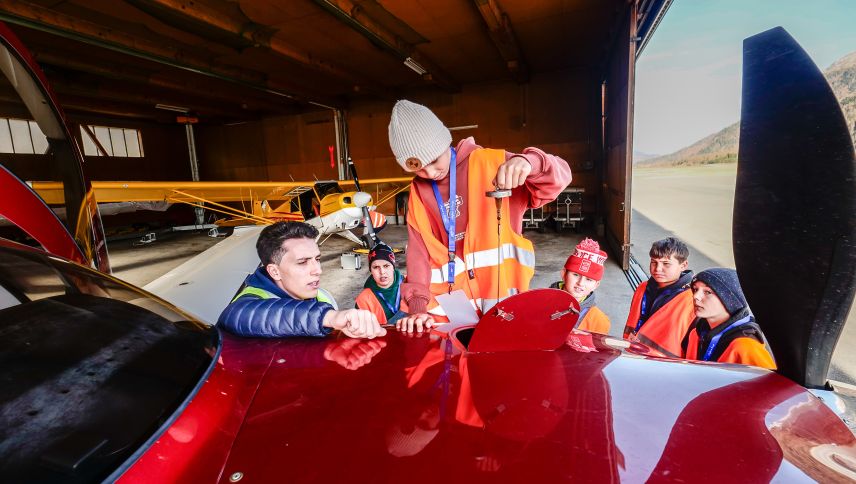 Air-Corviglia-Pilot Sandro Raffa lässt sich bei der Ölstandskontrolle an seiner Cirrus Turbo von den Schulkindern helfen.