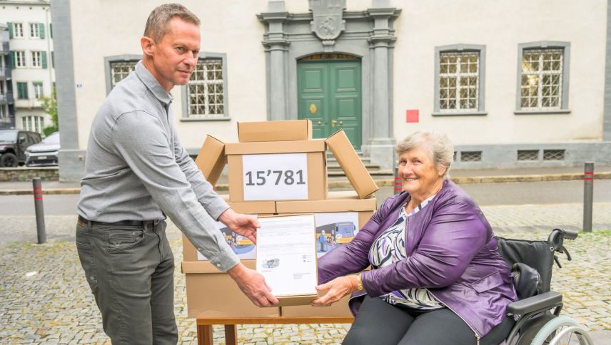 André Paganini von der Standeskanzlei Graubünden nimmt die Volksinitiative «Barzahlung bei öffentlichen Leistungen» aus den Händen der Initiantin Berta Caminada entgegen. Foto: Markus Casutt