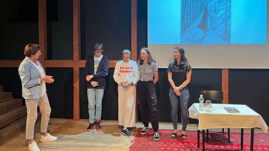 Trais scolars cun Letizia Könz (a schnestra) düraunt üna preschantaziun  insembel cun l’autura Valentina Parolini (a dretta). fotografia: mad