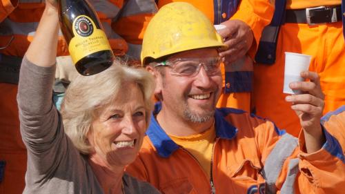 Die Gemeindepräsidentin Claudia Troncana stösst mit den Mineuren auf den Durchstich des Umfahrungstunnels an. Foto: Jon Duschletta 