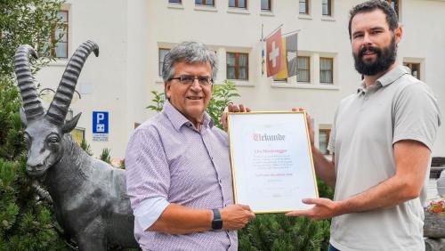 Urs Niederegger (links) erhält die Auszeichnung von Kilian Steiner von La Punt Ferien. Foto: z.Vfg/La Punt Ferien